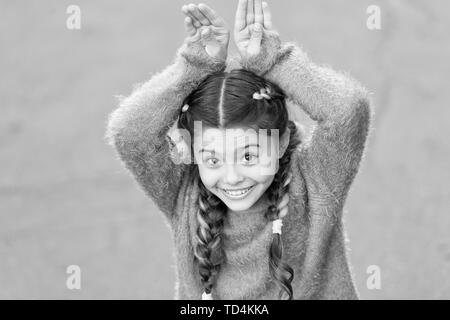 Cute Bunny. Frohe Ostern. Urlaub Bunny Girl posiert wie Kaninchen grauen Hintergrund. Kind lächelnd spielen Bunny Rolle. Verspieltes Baby feiern Ostern. Frühlingsferien. Talent und Handeln. Glückliche Kindheit. Stockfoto