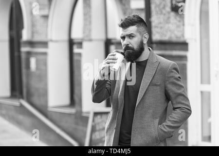 Kaffee trinken für Unterwegs. Geschäftsmann lumbersexual Erscheinungsbild genießen Sie Kaffee Pause aus Business Center. Entspannen und erholen Sie sich. Man bärtige hipster Pappbecher Kaffee trinken. Noch ein Schluck Kaffee. Stockfoto