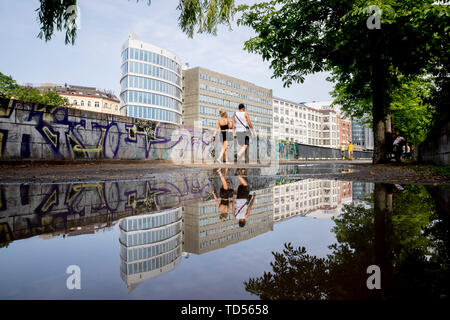 Berlin, Deutschland. 12 Juni, 2019. Wanderer zu Fuß entlang der Ufer der Spree zwischen Charlottenburg und Moabit, die sich in einer Pfütze widerspiegelt. Credit: Christoph Soeder/dpa/Alamy leben Nachrichten Stockfoto