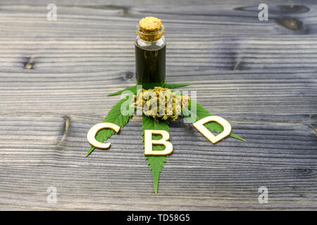 Holz- Buchstaben, die CBD ist die Abkürzung für Cannabidiol mit Cannabis Blütenknospen und Öl auf Holz- Tabelle Stockfoto