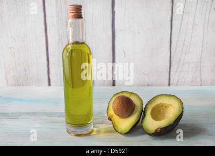 Avocadoöl erste Kaltpressung, im Glas, mit einer avocado Split auf hellem Holz. Stockfoto