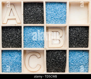 Holzkiste mit quadratischen Fächer teilweise mit blauen oder schwarzen Dekolack sand und mit den Buchstaben A, B und C in der freigegebenen Felder. Stockfoto