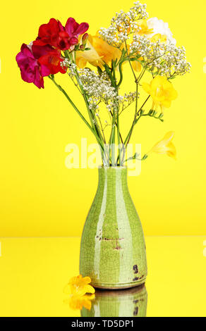 Schönen Blumenstrauß von Freesie in Vase auf gelbem Hintergrund Stockfoto