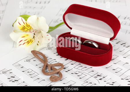 Violinschlüssel, Blume und Box holding Trauringe auf musikalischen Hintergrund Stockfoto