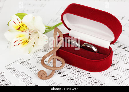 Violinschlüssel, Blume und Box holding Trauringe auf musikalischen Hintergrund Stockfoto