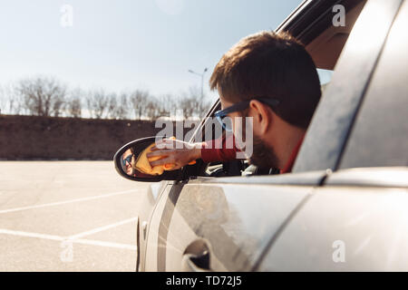 Bild von der Rückseite der Mann mit orange rag Waschen entfernten Auto Spiegel Stockfoto