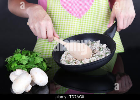Hände kochen Pilzsauce in Wanne auf grauem Hintergrund Stockfoto