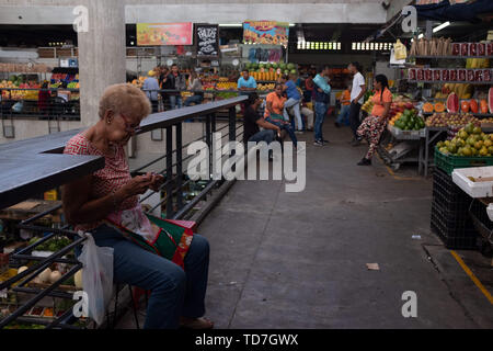 Caracas, Venezuela. 6. Juni, 2019. Eine Frau strickt an einem Markt in Caracas, Venezuela. Es ist mit Gemüse gefüllt. Dieser Markt hat Gemüse, weil niemand leisten können, sie zu kaufen, aber ein paar Wenige. Vor der Krise die Märkte waren immer mit Menschen shopping gefüllt. Jetzt sind sie leer aufgrund einer Krise mit Hyperinflation. Credit: Allison Abendessen/ZUMA Draht/Alamy leben Nachrichten Stockfoto