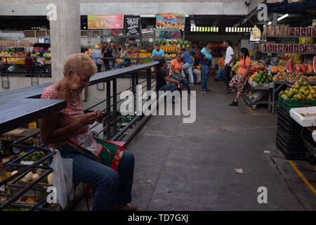 Caracas, Venezuela. 6. Juni, 2019. Eine Frau strickt an einem Markt in Caracas, Venezuela. Es ist mit Gemüse gefüllt. Dieser Markt hat Gemüse, weil niemand leisten können, sie zu kaufen, aber ein paar Wenige. Vor der Krise die Märkte waren immer mit Menschen shopping gefüllt. Jetzt sind sie leer aufgrund einer Krise mit Hyperinflation. Credit: Allison Abendessen/ZUMA Draht/Alamy leben Nachrichten Stockfoto