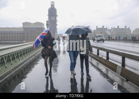 London, Großbritannien. 13. Juni, 2019. Fußgänger halten Regenschirme während einer sintflutartigen Regenfällen während der Überquerung der Westminster Bridge in London. Credit: Amer Ghazzal/SOPA Images/ZUMA Draht/Alamy leben Nachrichten Stockfoto