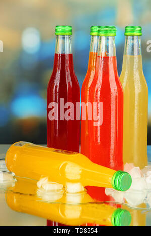 Flaschen mit leckeren Drinks mit Eiswürfeln, auf hellen Hintergrund Stockfoto