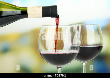 Rotwein in Glas Wein gegossen, auf hellen Hintergrund Stockfoto