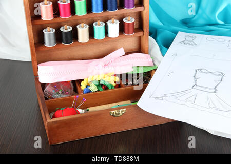 Nähset im Holzkasten, Tuch und Skizze auf dem Holztisch Stockfoto