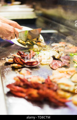 Ein Koch ist dabei ein Seafood Grill für die Cafeteria, dampfende mit Hummer, Garnelen, Muscheln und mehr, die sehr lecker aussieht. Stockfoto