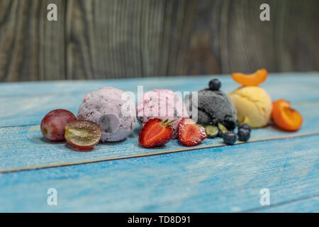 Süßes Eis in Kugeln auf einem Holz- Hintergrund. Verschiedene Aromen Beeren und Früchten. Platz kopieren Stockfoto