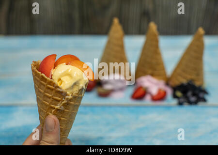 Süßes Eis in Kugeln auf einem Holz- Hintergrund. Dessert mit verschiedenen Aromen und frische Beeren und Früchte. Eis in der Waffel Kegel. Platz kopieren Stockfoto