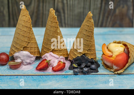 Süßes Eis in Kugeln auf einem Holz- Hintergrund. Dessert mit verschiedenen Aromen und frische Beeren und Früchte. Eis in der Waffel Kegel. Platz kopieren Stockfoto