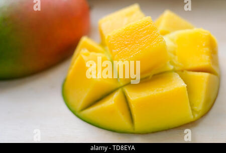 Reife saftige Gelbe exotische Mango in Würfel schneiden auf Holz- Hintergrund. Tropische Delikatesse voller Vitamine für eine gesunde Ernährung. Detailansicht. Selektive foc Stockfoto