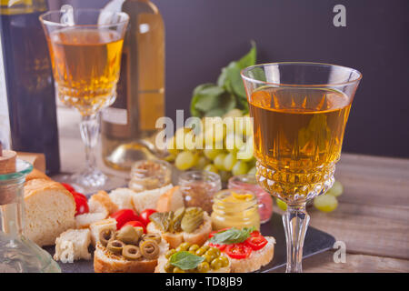 Italienische bruschetta im Sortiment auf der Platte. Frische hausgemachte Bruschetta oder Crostini und Zutaten, Gläser mit weißen Wein, Trauben, Fondue. Party o Stockfoto