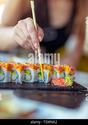 Lecker California Roll, eine Frau mit Stäbchen isst, leckeren, gesunden Sushi, genießen Sie orientalisches Essen, Mittagessen in Luxus Sushi Restaurant. Stockfoto