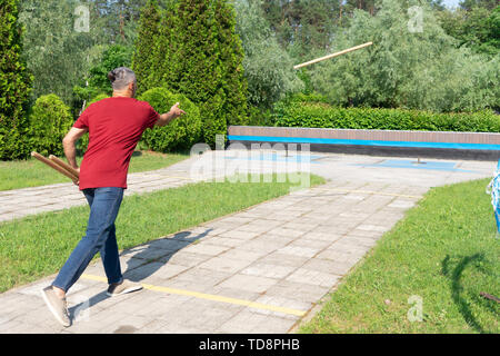 Mann spielt gorodki, beliebten alten russischen und skandinavischen folk Sport Stockfoto