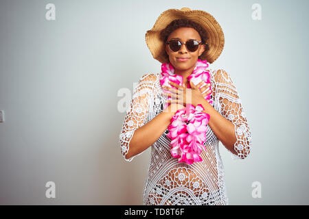 Junge afrikanische amerikanische Frau mit afro Haar Blume von Hawaii Lei über isolierte Hintergrund lächelnd mit der Hand auf der Brust mit geschlossenen Augen und Grat Stockfoto