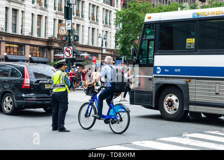 New York City, USA - 31. Juli 2018: Die muslimische Frau Polizeioffizier, der Richtung des Verkehrs auf der Straße, während ein Radfahrer geht in Manhattan, New York City, USA Stockfoto