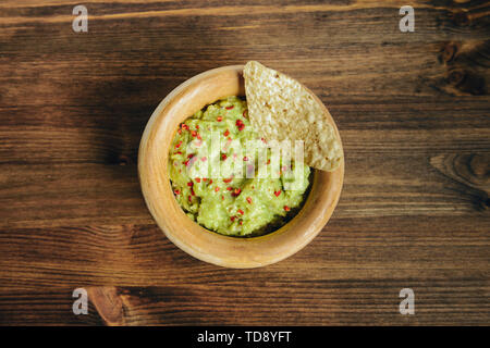 Selbstgemachte guacamole mit Nachos in einem Holz Schüssel auf einem Holztisch, typisch mexikanischen Gesunde vegane Küche, Ansicht von oben Stockfoto