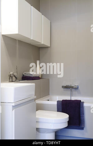 Violett Handtücher drapiert über der Badewanne rim Im minimalistischen Badezimmer Großbritannien & Irland NUR VERWENDEN Stockfoto