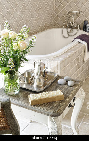 Kerzen und eustoma Blumenstrauß in Glasvase stehen auf Französisch Ende Tabelle vor der Badewanne im klassischen Stil Schlafzimmer Großbritannien & Irland NUR VERWENDEN Stockfoto