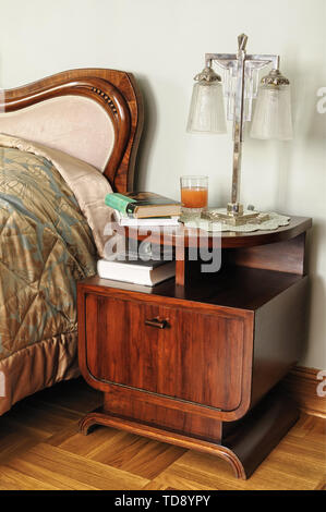Holz- art deco Beistelltisch neben bequemen Bett im Retro-stil Schlafzimmer Großbritannien & Irland NUR VERWENDEN Stockfoto