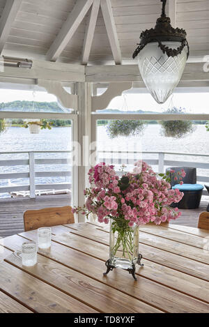 Rosa Blumen in klarem Glas Blumenvase auf dem Tisch im Pavillon mit Blick auf den See britische und irische NUR RECHTE Stockfoto