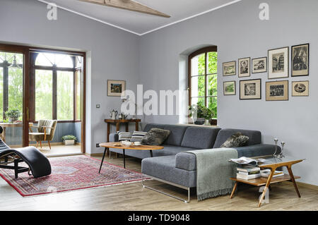 Tisch vor Grauen Sofa in ein geräumiges Wohnzimmer mit Blick auf den Wintergarten DES VEREINIGTEN KÖNIGREICHS UND IRLANDS NUR RECHTE Stockfoto