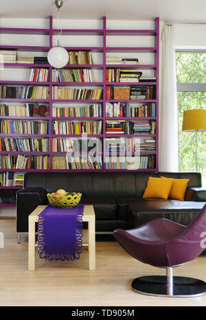 Schwarz Leder Sofa vor lila Bücherschrank, VK und Irland NUR VERWENDEN Stockfoto