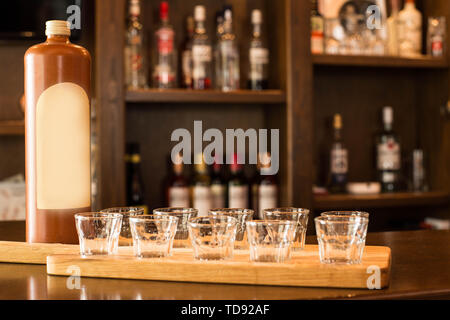 Leere Shot Gläser und Spirituosen warten auf den Zähler für die Partei zu beginnen, in einer Bar mit Alkohol auf dem Hintergrund Stockfoto