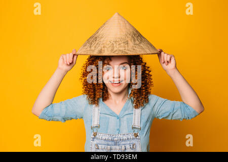 Rothaarige curly Frau in einer Chinesischen hat ist Lachen, auf einem gelben Hintergrund. Reisen in den Osten, China und Asien. Stockfoto