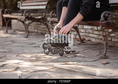 Der junge Mann Beine in Schuß, das Setzen auf Inline Skates. Stockfoto