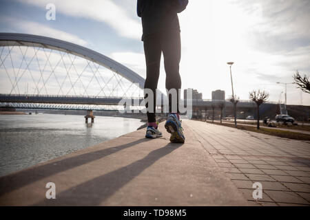 Ein Mann, nicht erkennbare Person, Athleten mit Sport Kleidung und Laufschuhe, wandern oder joggen auf dem Asphalt. Schuß von der Rückseite, Ansicht von hinten. Stockfoto