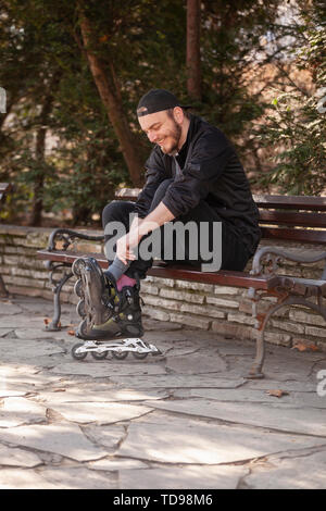 Ein junger Mann, seine Inline Skates auf die Füße. Stockfoto