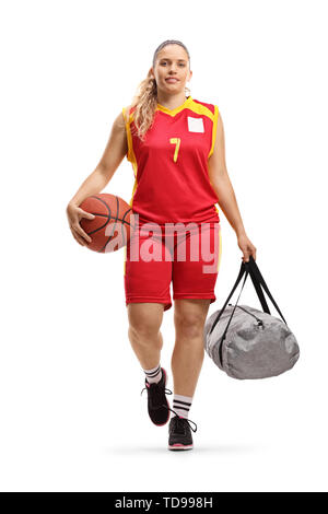 In voller Länge Porträt eines weiblichen Basketball Player in einem Jersey zu Fuß und mit einer Kugel und einer Sporttasche auf weißem Hintergrund Stockfoto