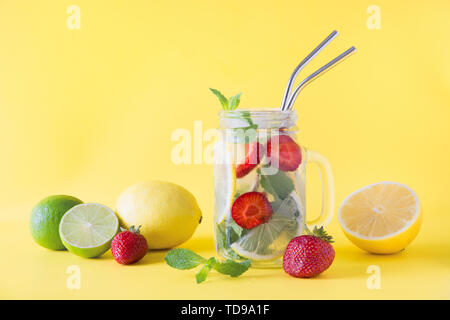 Detox Wasser, Limonade oder Mojito mit Zitrone, Limone, Erdbeere im Marmeladenglas auf Gelb. Sommer gesunde frische Getränk. Platz für Text. Horizontale orient Stockfoto