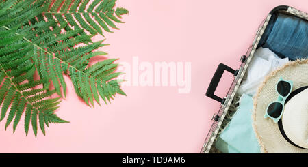 Blatt von Farn, tropischen detox Wasser und offenen Koffer mit Kleidung auf Pastell rosa Hintergrund. Ansicht von oben mit der Kopie. Sommer Konzept reisen. Stockfoto