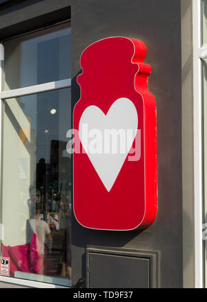 Große rote cartoon Glas mit einem weißen Herzen an der Wand hängen nächsten Store Kerze Stockfoto