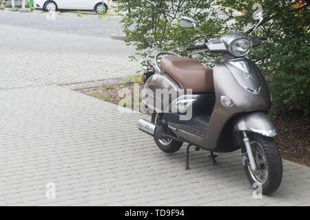 Gdansk Oliwa, Polen - Juni 7, 2019: Grau vintage Romet scooter stehen auf dem Bürgersteig an einem bewölkten Tag mit Parkplatz und Baum im Hintergrund Stockfoto