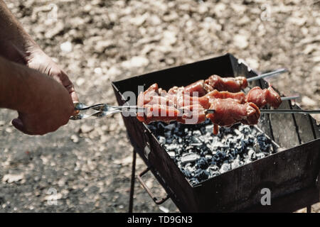 Mann hält in der Hand einen Spieß mit rohem Fleisch, Life Style. Stockfoto