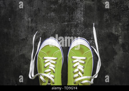 Blau - blaugrün - Grün - türkis Sneaker mit Ungebundener Schnürsenkel auf einem dunklen konkreten Hintergrund. Kopieren Sie Platz. Ansicht von oben Stockfoto