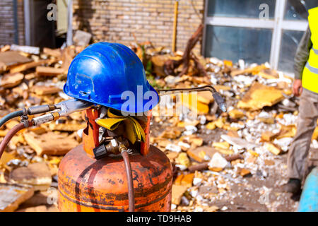 Verwendet gas schweißen Ausstattung zum Schneiden von Schrott, Zylinder mit Propan und Stickstoff, Handschuhe und blauen Helm, Acetylen Fackel. Stockfoto