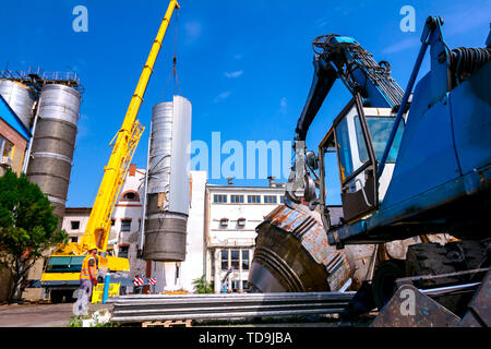 Lader Maschinen mit hydraulischer grappling Klaue und Kran sind die heavy metal Silo in industriellen Komplexes. Stockfoto