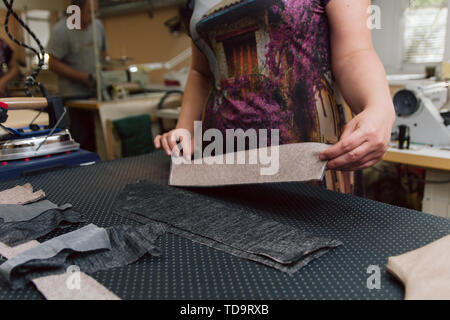 Eine Frau, die Anschläge der Stoff für weitere Nähen. Bügeln mit industriellen Eisen. Stockfoto