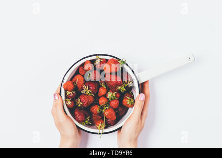 Sieb rote reife Erdbeeren in der Frau Hände, Ansicht von oben auf weißem Hintergrund. Stockfoto